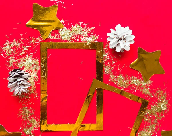 Merry Christmas and Happy New Year. Flat lay photo with golden mockup photo frames and Christmas decorations on bright red background. Xmas greeting card, banner. Copy space for the text