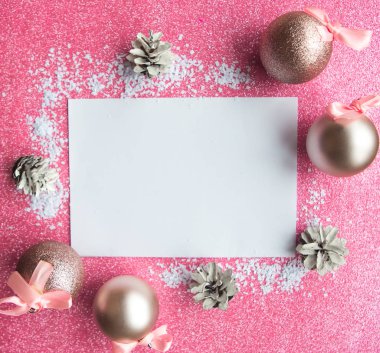 Noel kompozisyonu. Beyaz model boş ve pembe arka planda Noel süslemeleri. Noel, kış, yeni yıl konsepti. Düz konum, üst görünüm, kopyalama alanı