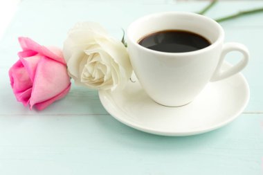 Kahve fincanı ve güller ahşap masada 