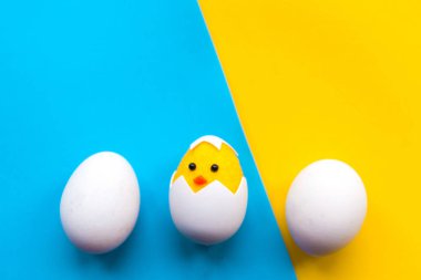 Parlak mavi ve sarı arka planda oyuncak tavuk ve yumurta. Metin için alanı kopyala. Paskalya konsepti