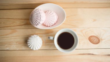 Beyaz zefir ve kahve fincanı ahşap masanın üstünde.. 