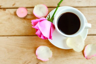 Kahve fincanı ve ahşap arka planda pembe gül. Aşk konsepti. Düz yatış, üst görünüm