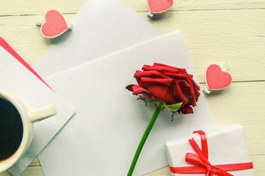 Aşk kompozisyonu - kırmızı gül, kahve fincanı ve tahta masa üzerinde hediye kutusu
