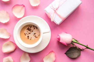 Love composition - coffee cup, gift box and pink rose on pink background, top view. Valentines Day greeting card