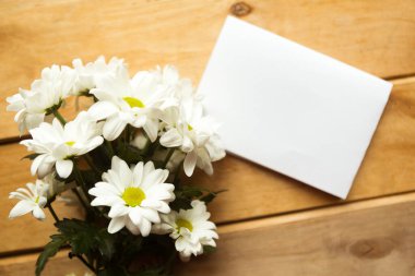 Bir buket beyaz çiçek ve ahşap arka planda beyaz bir model. Düz konum, üst görünüm, kopyalama alanı