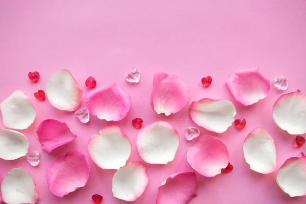 White and pink rose petals on pink background. Copy space for the text