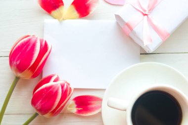 Kahve fincanı, hediye kutusu ve ahşap arka planda kırmızı laleli düz bir fotoğraf. Güzel Anneler Günü, Kadınlar Günü ya da Sevgililer Günü tebrik kartı. Anneler Günü tebrik kartı.