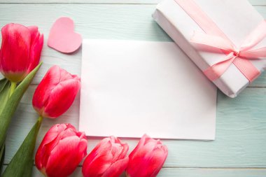 Pembe laleler, hediye kutusu ve tahta arka planda beyaz model. Düz konum, üst görünüm, kopyalama alanı. Paskalya ya da Anneler Günü tebrik kartı