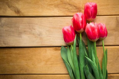 Ahşap arka planda pembe laleler. Düz konum, üst görünüm, kopyalama alanı. Paskalya ya da Anneler Günü tebrik kartı