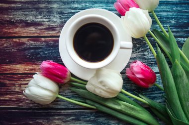 Kahve fincanı ve ahşap arka planda laleler.