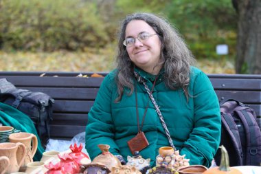 Minsk / Belarus - 31 Ekim 2018: Gözlüklü bir kadın parktaki bankta oturuyor