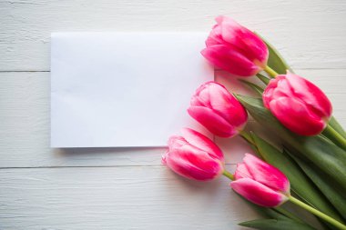 Pembe laleler ve ahşap arka planda beyaz model. Düz konum, üst görünüm, kopyalama alanı. Kadınlar Günü ya da Anneler Günü tebrik kartı.