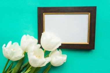 Beyaz lale buketi ve parlak yeşil arka planda fotoğraf çerçevesi.