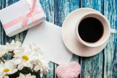 Kahve fincanlı düz bir fotoğraf, hediye kutusu ve ahşap arka planda bir buket çiçek. Metin için alanı kopyala. Doğum günü veya Anneler Günü tebrik kartı