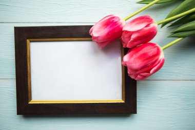 Ahşap arka planda pembe laleler ve fotoğraf çerçevesi. Paskalya ya da Anneler Günü tebrik kartı