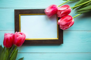 Ahşap arka planda pembe laleler ve fotoğraf çerçevesi. Paskalya ya da Anneler Günü tebrik kartı