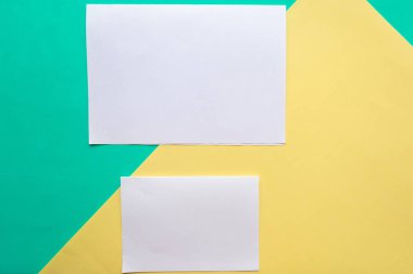 Beyaz kağıt modeli yeşil ve sarı geometrik kağıt arkaplan üzerinde boş, minimal konsept