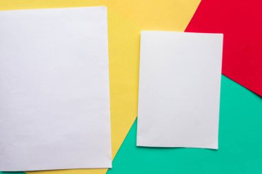 Yeşil, kırmızı ve sarı geometrik kağıdın arka planında iki beyaz model boş, minimum konsept