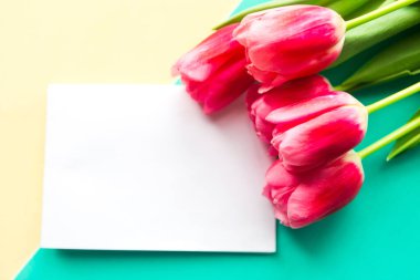 Bir buket pembe lale ve sarı ve yeşil arka planda beyaz model. Paskalya ya da Anneler Günü tebrik kartı. Metin için alanı kopyala