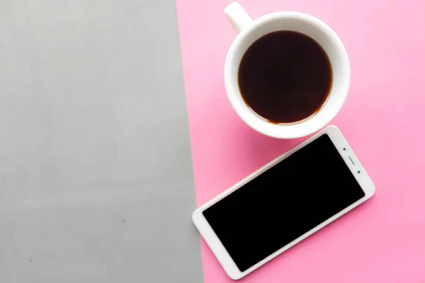 グレーとピンクのパステルの背景にコーヒーカップとモックアップモバイル 最上階だ ミニマルなコンセプト — ストック写真