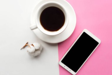 Siyah model cep telefonu ve pembe ve beyaz arka planda kahve fincanı. Asgari konsept