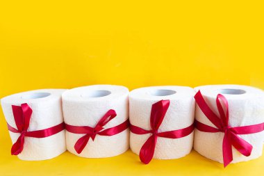 Hediyeye sarılı tuvalet kağıdı ruloları. Parlak sarı arka plan. Metin için alanı kopyala. Covid19 konsepti