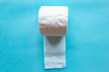 Mavi arka planda yumuşak, beyaz tuvalet kağıdı rulosu