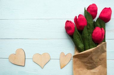 Ahşap zemin üzerinde kırmızı el işi kağıt laleler.