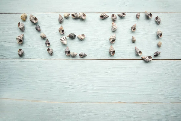 Word Summer in russian letters from seashells on wooden background. Summer vacation concept