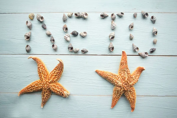 Word Summer in russian letters from seashells on wooden background. Summer vacation concept
