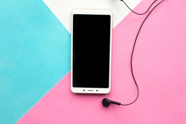 Geometrik pembe, beyaz ve mavi kağıt arka plan desenli telefon ve kulaklıklar. En düşük konsept