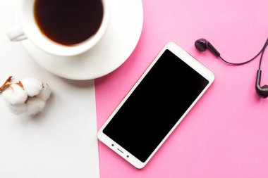 Pembe arka planda kahve fincanı ve cep telefonu olan düz bir fotoğraf.. 