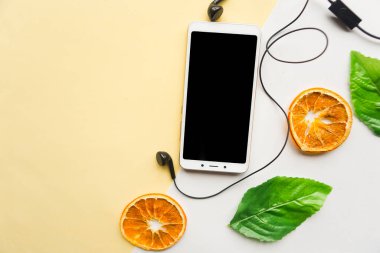 Siyah model ekranlı cep telefonu ve sarı arka planda kulaklık. Asgari konsept