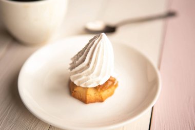 Kremalı kek ve kahve fincanı ahşap masada.