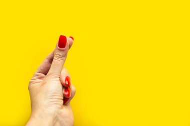 Kadın elinin el hareketi yaptığı yakın çekim görüntüsü. Parlak sarı arkaplanda izole edilmiş. 