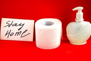 Tuvalet kağıdı rulosu, sıvı sabun ve mesaj parlak kırmızı arka planda evde kal. Karantina konsepti