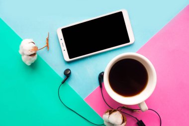 Renkli arka planda kahve fincanı ve cep telefonu olan düz bir fotoğraf.. 