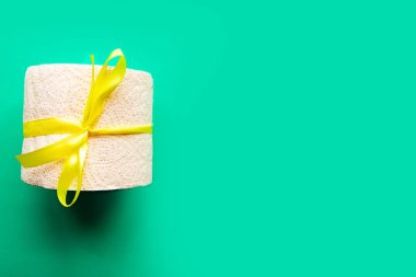 Yeşil arka planda hediye yayı ile sarılmış tuvalet kağıdı rulosu. Covid19 konsepti. Metin için alanı kopyala