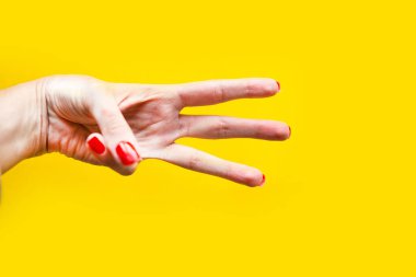 Kadının eli, parlak sarı arka planda üç hareket gösteriyor.