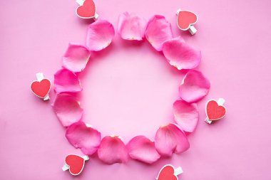 Pembe arka planda gül yapraklarından oluşan yuvarlak bir çerçeve. Aşk konsepti