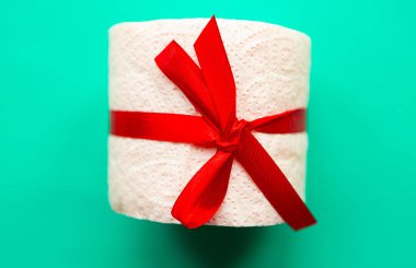 Yeşil arka planda hediye yayı ile sarılmış tuvalet kağıdı rulosu. Covid19 konsepti