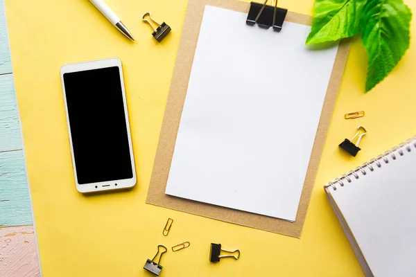 黄色の背景に白のモックアップブランクと黒のモックアップ電話 オフィスコンセプト — ストック写真