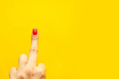 Parlak sarı arka planda orta parmağını gösteren bir kadın eli. Minimum konsept. Metin için alanı kopyala