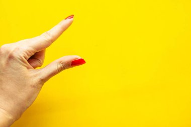 Kadın eli oluşturan hareketin yakın görüntüsü. Parlak sarı arkaplanda izole edilmiş. 