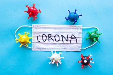 Corona kelimesinin ve renkli virüslerin olduğu tıbbi maske. Coronavirus konsepti