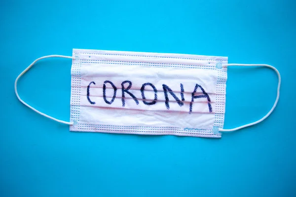 Medical mask with word Corona on blue background. Covid-19 concept