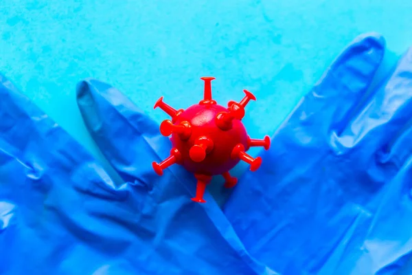 Medical gloves and virus on blue background. Covid-19 concept