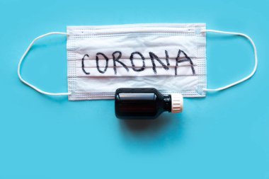 Tıbbi maske ve mavi arka planda bir şişe hap.