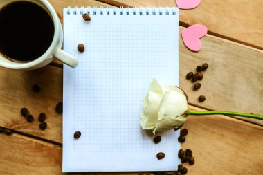 Defteri aç, kahve fincanı ve tahta arka planda beyaz gül. Güzel tebrik kartı.