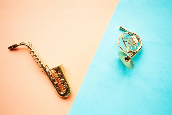 Oyuncak saksafon ve Fransız kornosu geometrik mavi ve pembe arka plan, üst görünüm